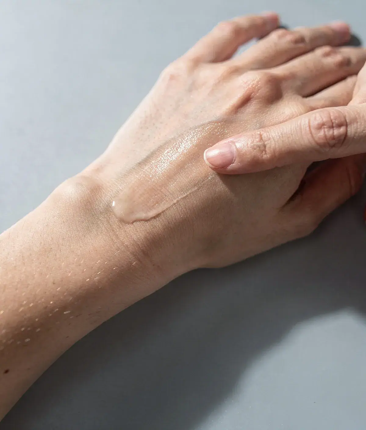 Detalle de un dedo deslizando sobre un antebrazo para comprobar la absorción de una crema corporal.