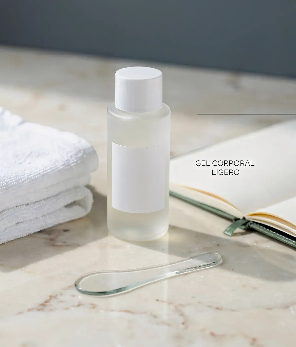 Frasco opalino de gel corporal ligero sobre mármol crema con toalla blanca y espátula de vidrio.