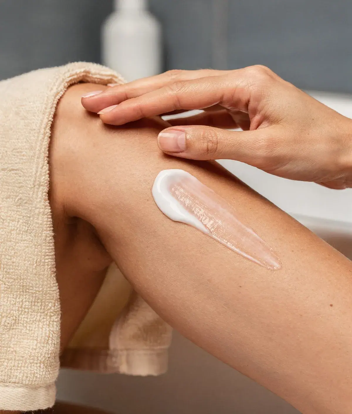 Crema corporal extendiéndose sobre la pierna durante un masaje suave.  