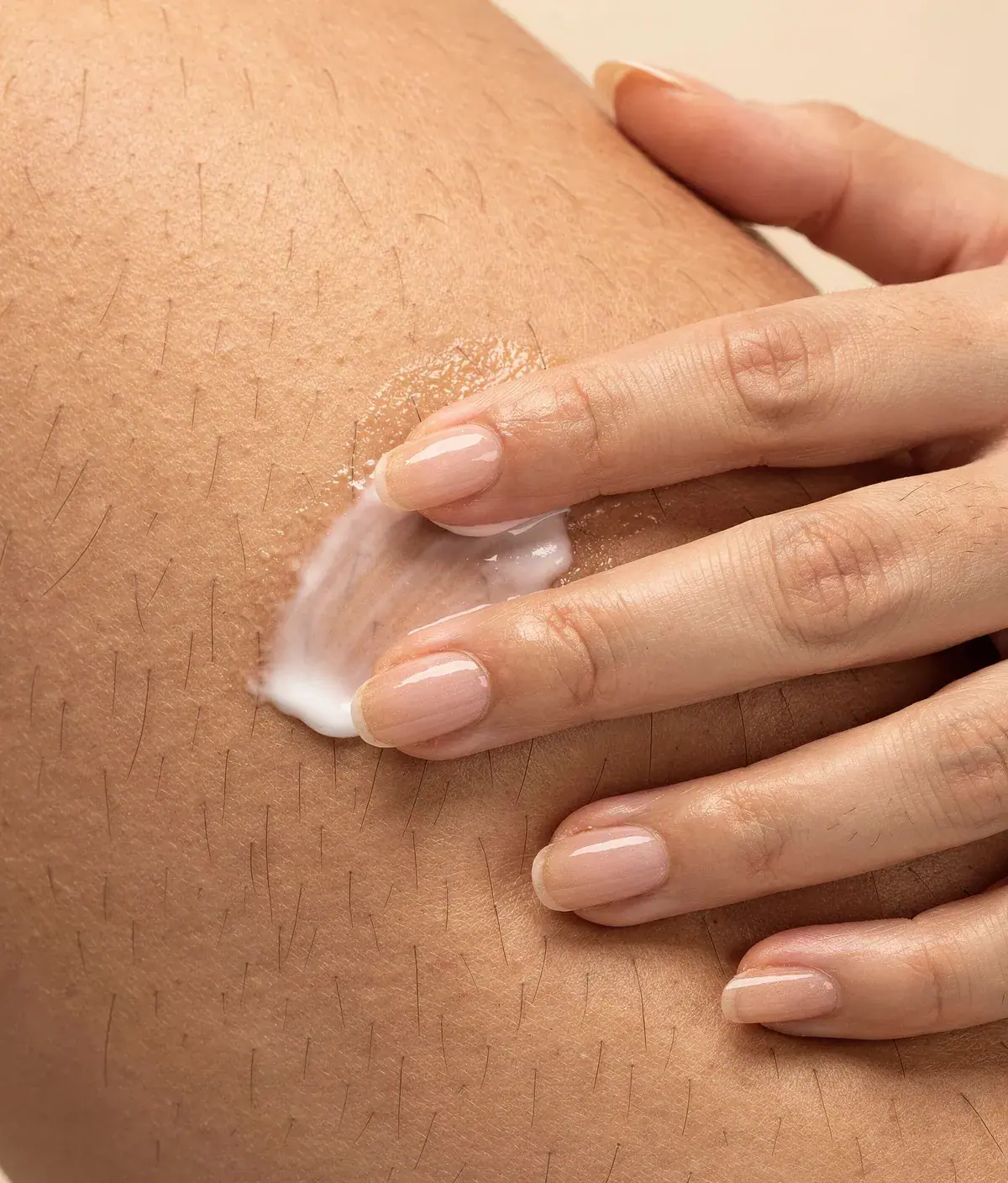 Primer plano de la textura natural de la piel del muslo con crema corporal absorbiéndose